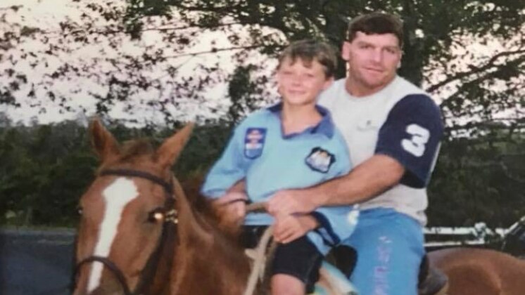 Damien Cook on a horse with his father dressed in a NSW Blues jersey.