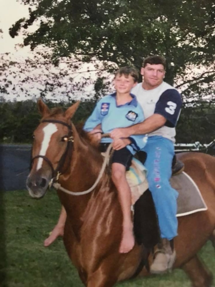 Damien Cook on a horse with his father dressed in a NSW Blues jersey.