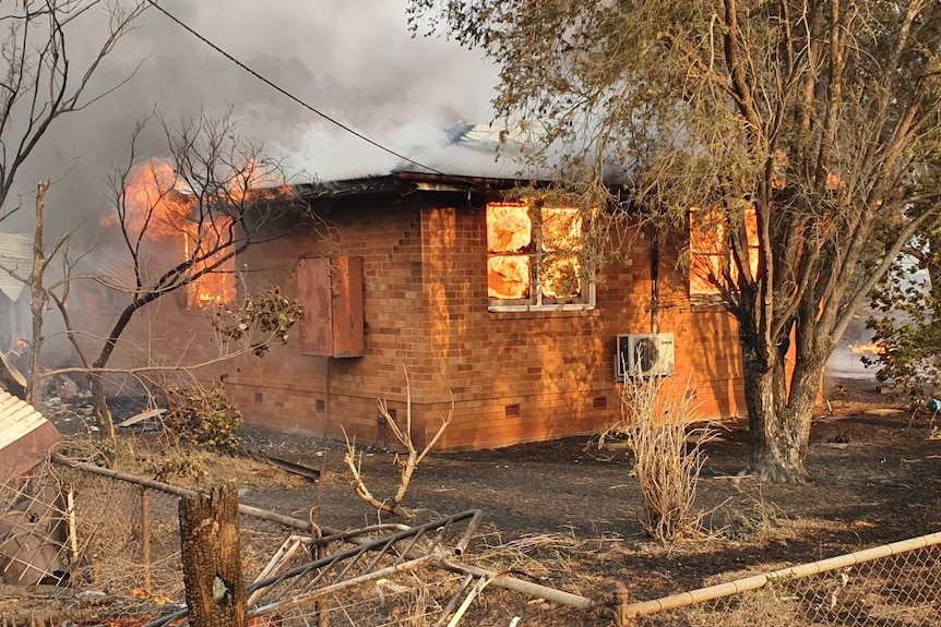 A small house with flames inside.