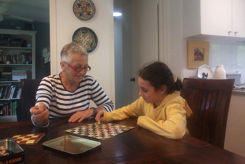 Wendy Lawson and her grand-daughter Gabby playing a board game at a wooden dining table