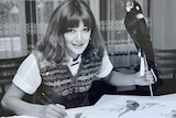 A black and white photo of a woman with a bird on a stick, and paint brushes