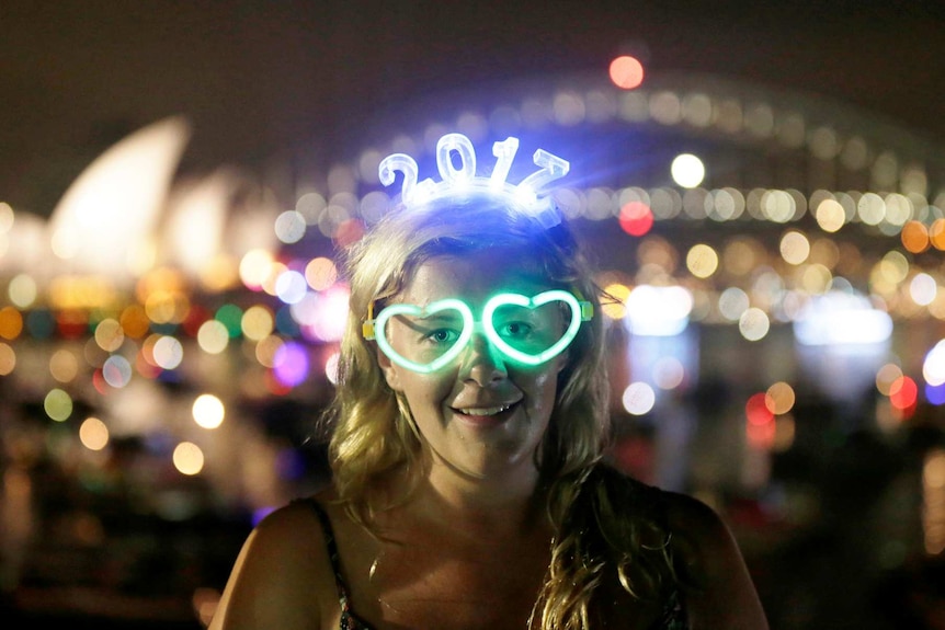 A woman wears glowing glasses and a headset for 2017 before watching the New Year's Eve fireworks in Sydney.