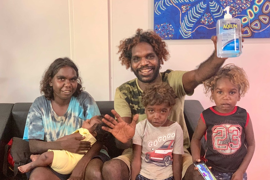 An Aboriginal family sits on a couch smiling