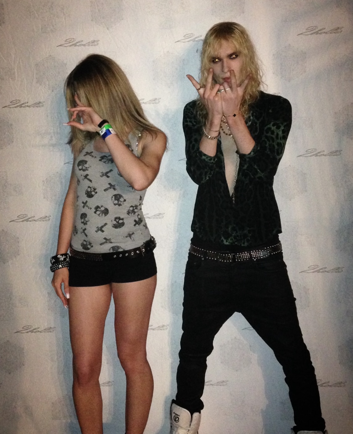 A young woman with face turned, 2hollis standing next to her holding up his fingers in a rock star gesture