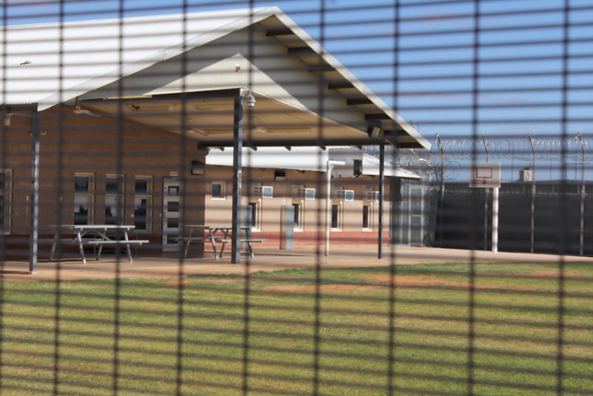 A photo of a basketball court taken through a mesh fence.