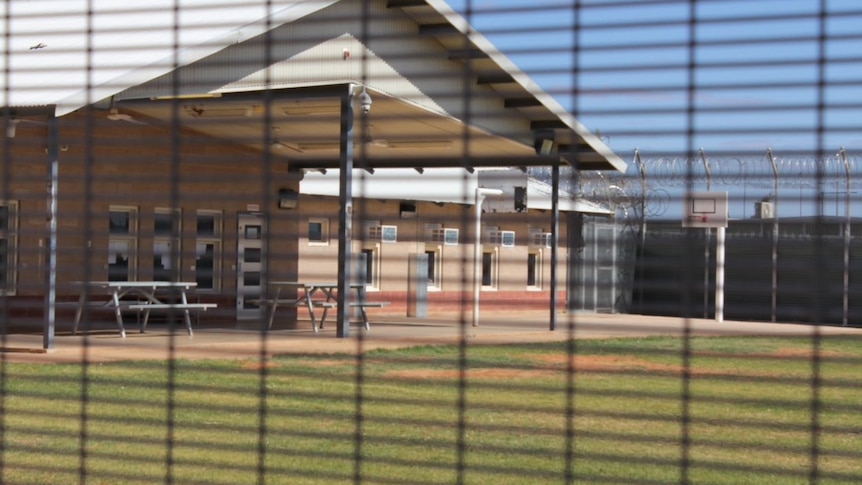 A photo of a basketball court taken through a mesh fence