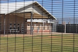 A photo of a basketball court taken through a mesh fence