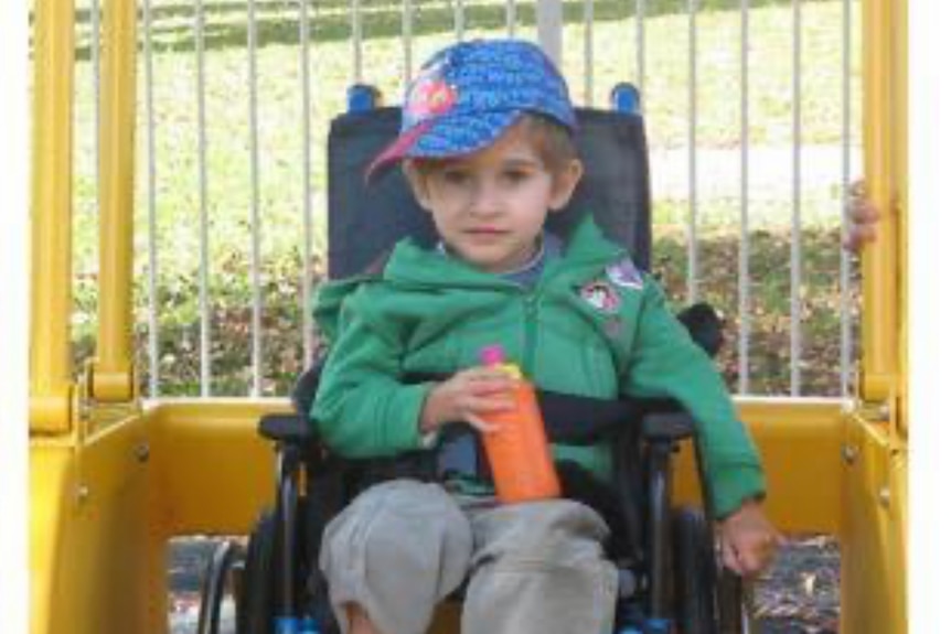 Jacob as an infant in a wheelchair holding a drink bottle.