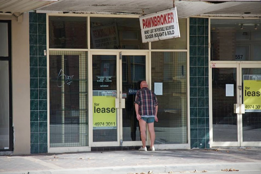 A man peers into the empty window of a shop