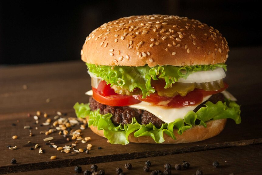 A burger on a plate, with lettuce and tomato.