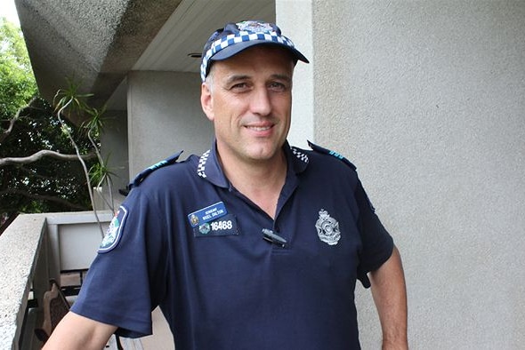 A police officer in uniform smiles