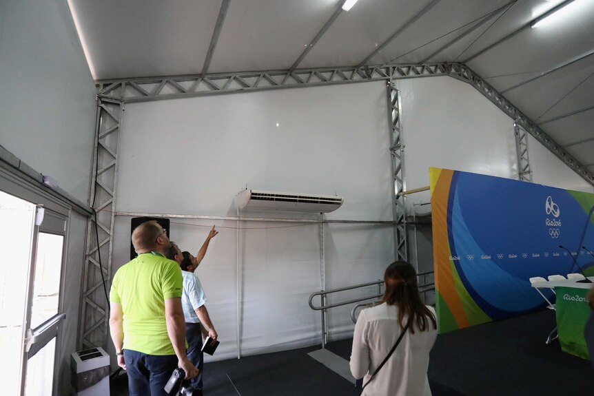 Venue staff inspect bullet hole in media tent