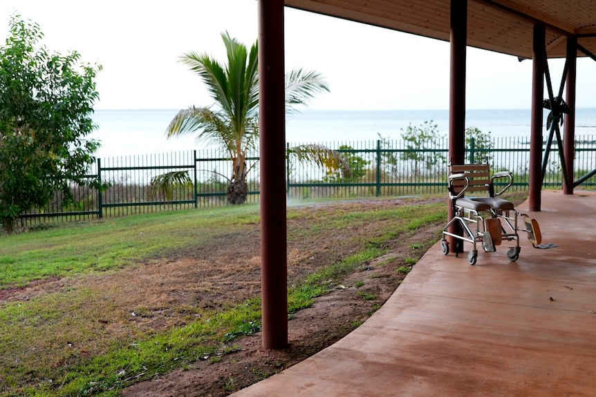 An empty wheelchair on a balcony with a bay in the background