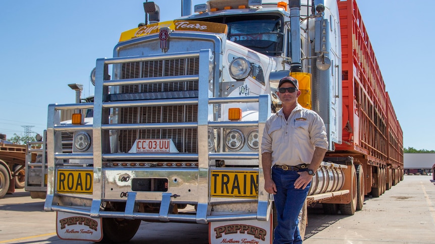 a man standing next to a road train.