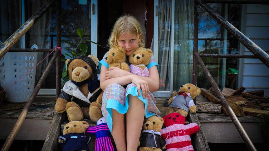 Paige Humphreys sitting on steps cuddling teddy bears