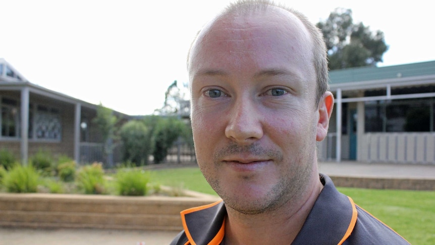 Man with receding hairline in a polo shirt looking at camera in tight frame