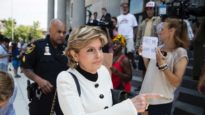 Celebrity lawyer Gloria Allred walks past women holding signs supporting Bill Cosby outside a Pennsylvania courthouse.