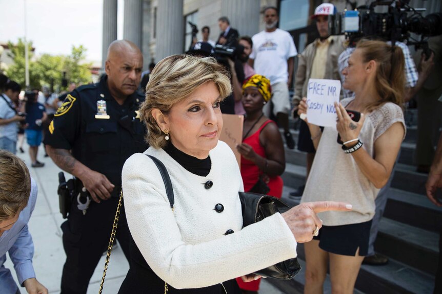 Celebrity lawyer Gloria Allred walks past women holding signs supporting Bill Cosby outside a Pennsylvania courthouse.