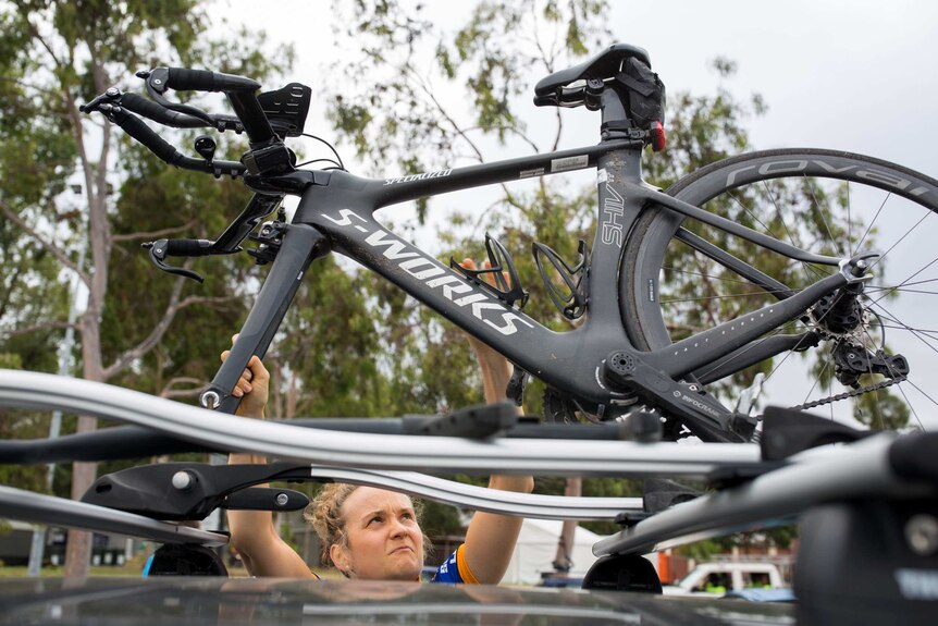 Paralympian cyclist Hannah Macdougall puts her bike on a roof rack.
