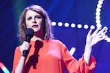 Comedian Anne Edmonds on stage with a mic in hand