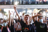 Pro-democracy protesters light flashlights from their phones during a rally.
