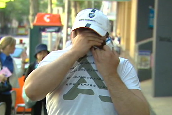 Kamel Khoder covers his face with his hands as he walks away from court.