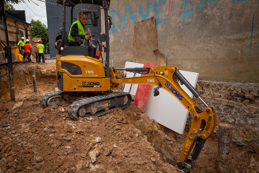 A young woman operating an excavator on a building site