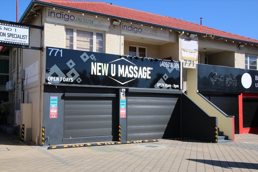 A photo of a sign reading New U Massage with two closed roller doors.