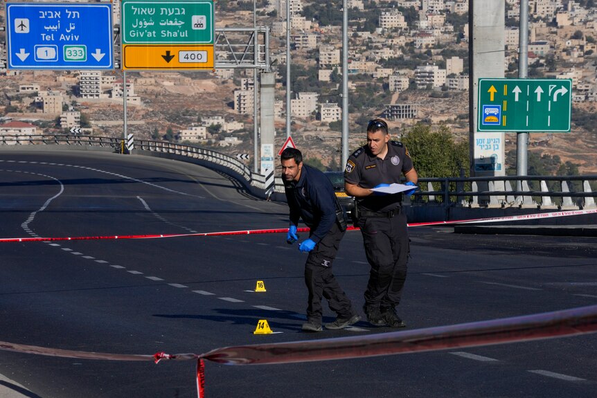 Israeli police inspect the scene of an explosion at a bus stop in Jerusalem.