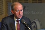 David Murray sits at a microphone in front of an ABC Radio National sign