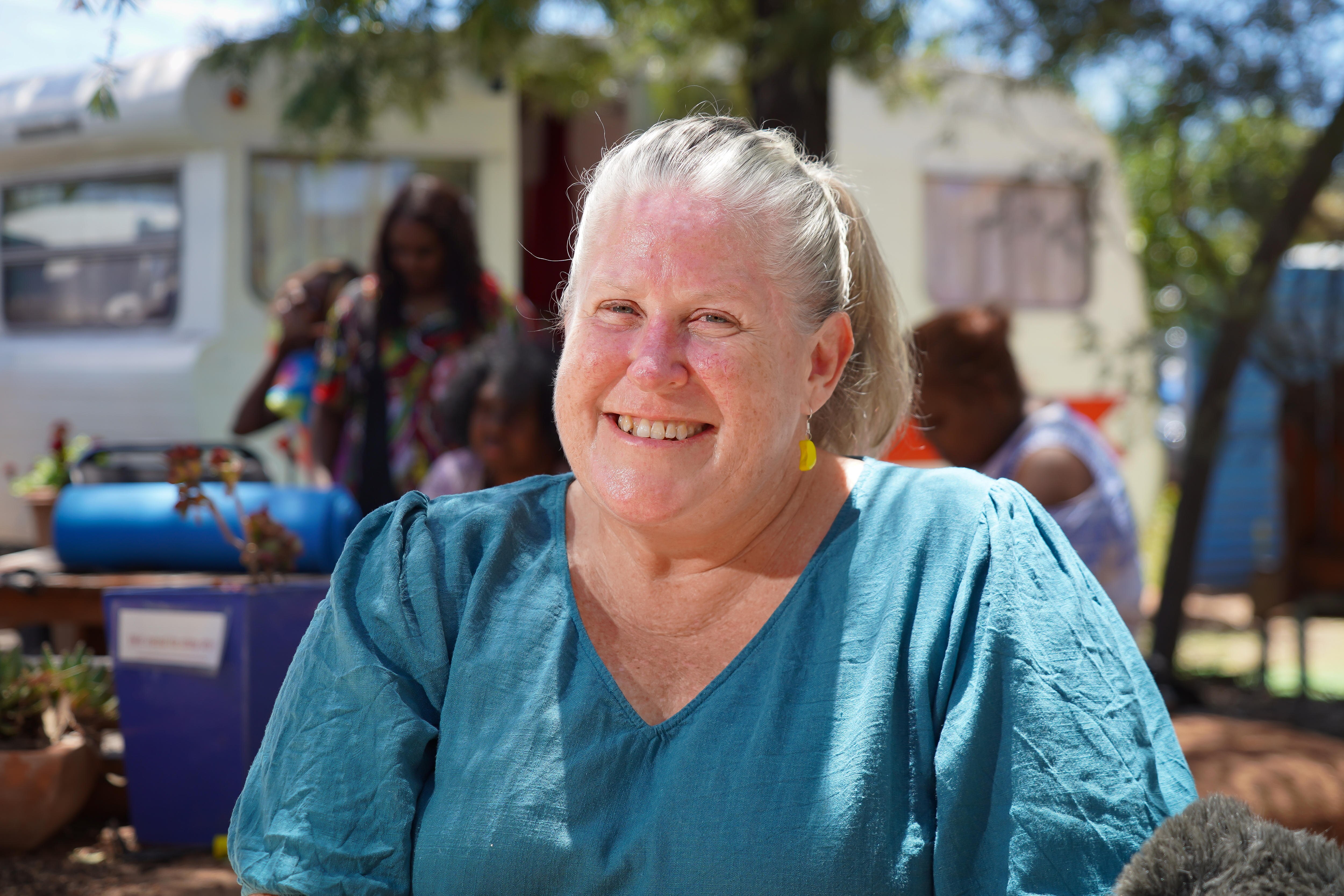 A woman in a blue shirt smiles at the camera