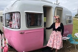 Monica is in pretty dress standing outside her Sunliner caravan at the 60th anniversary celebration in Forster