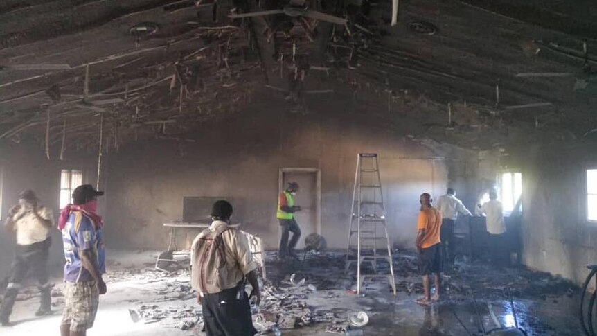 Workers survey damage in a burnt out room.