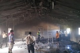 Workers survey damage in a burnt out room.