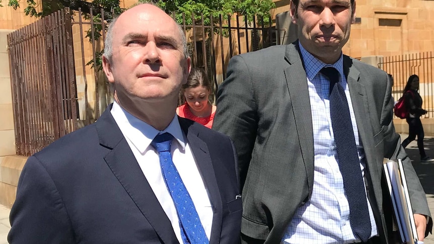 Two men in suits on a footpath outside court