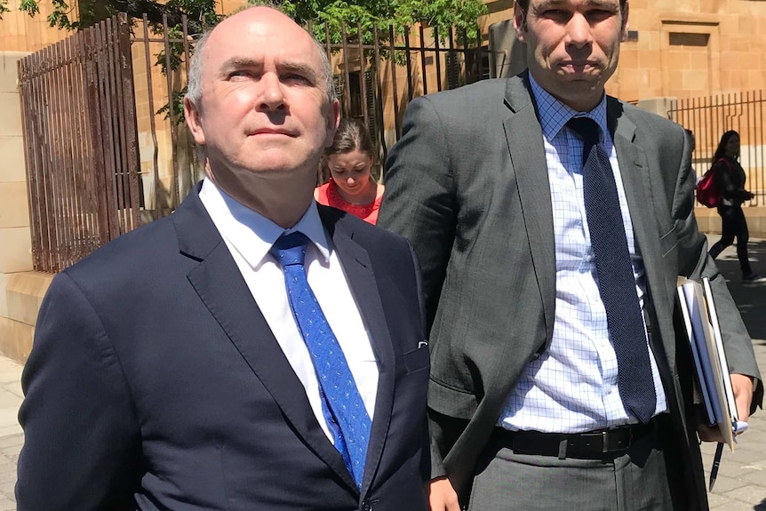 Two men in suits on a footpath outside court