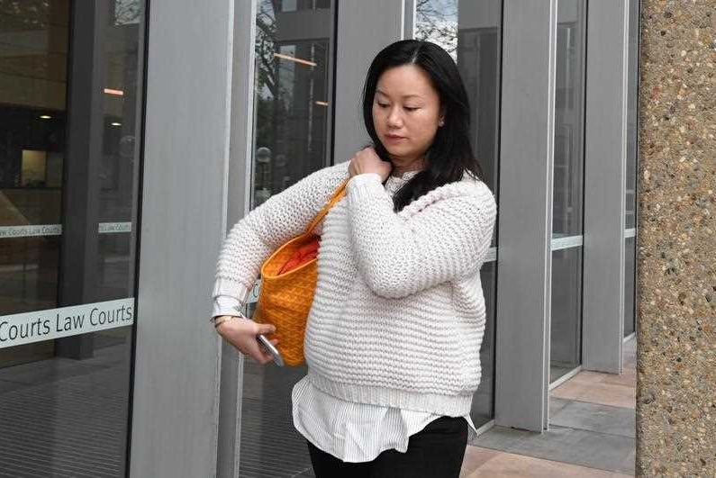 A woman in a white jumper walking along a street.