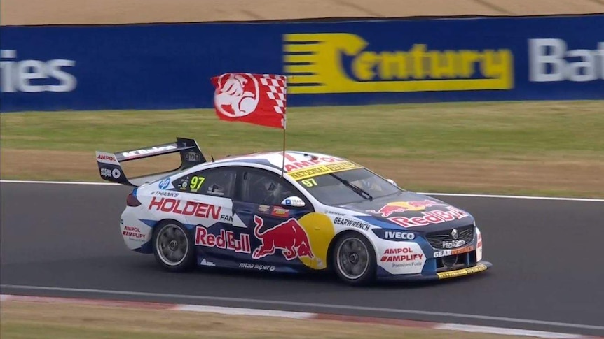 A large Holden flag flies out the side of Shane van Gisbergen's car at Bathurst.