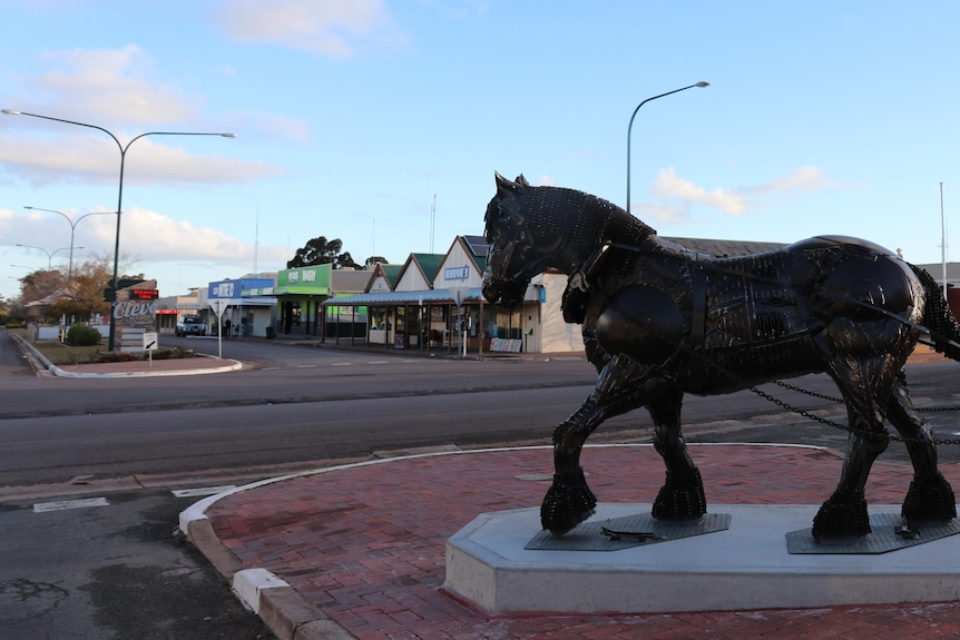 Town street scene with iron horse statue in foreground on right