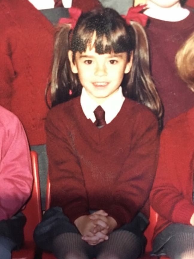 A girl with pigtails smiles for a school photo