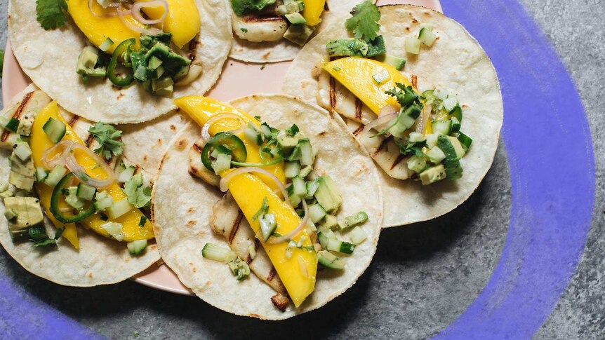 Five tacos with a filling of mango slices, haloumi, and cucumber and avocado salsa