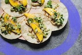 Five tacos with a filling of mango slices, haloumi, and cucumber and avocado salsa