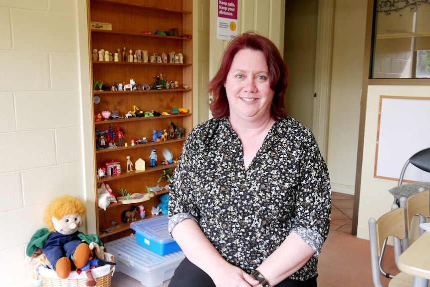 A woman with red hairs sits in a room with toys