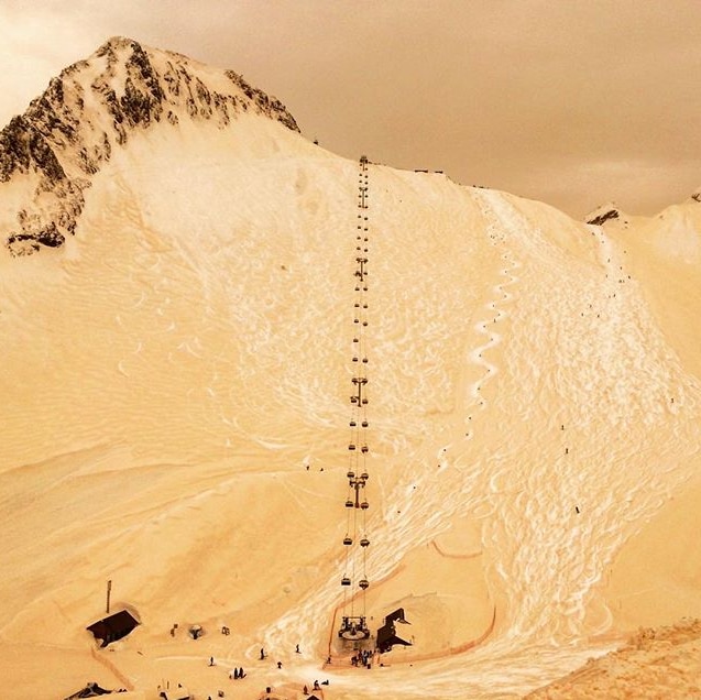 A ski lift going up a mountain covered with orange snow.