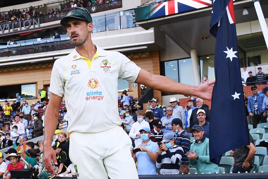 Mitchell Starc touches an Australian flag as he walks onto Adelaide Oval