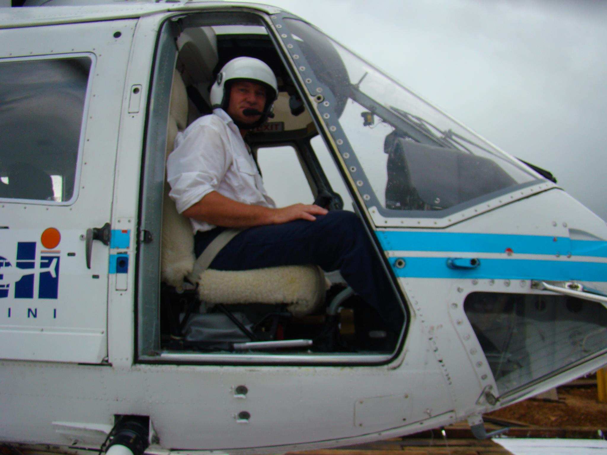 A man sitting at the controls of a helicopter