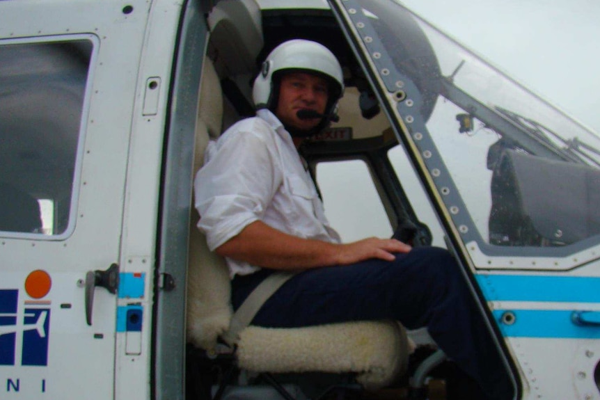 A man sitting at the controls of a helicopter