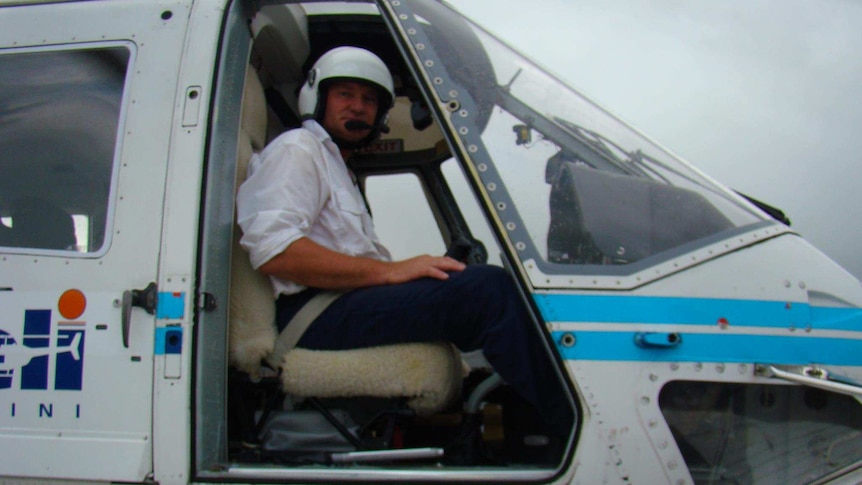 A man sitting at the controls of a helicopter