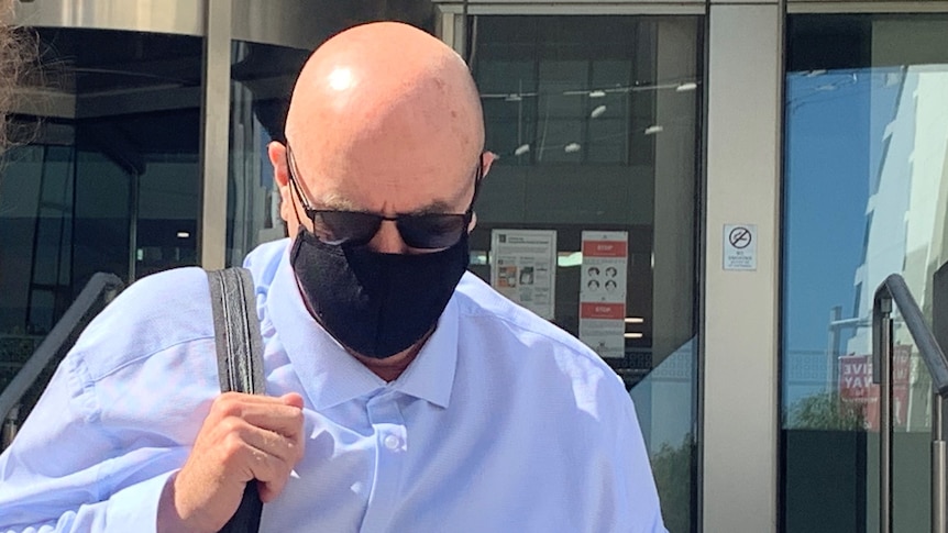 Simon Tugwell leaves court wearing sunglasses and a mask