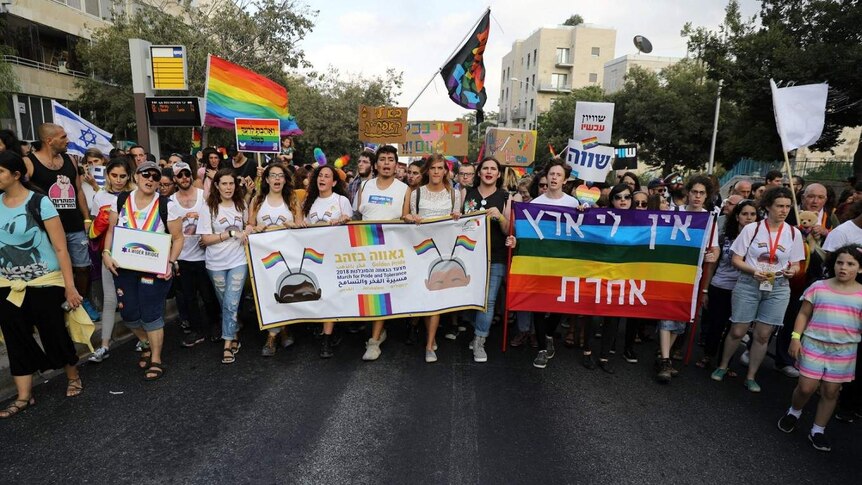 Marchers in Jerusalem's 2018 Gay Pride parade carrying rainbow banners and placards, one reading "I don't have another country"